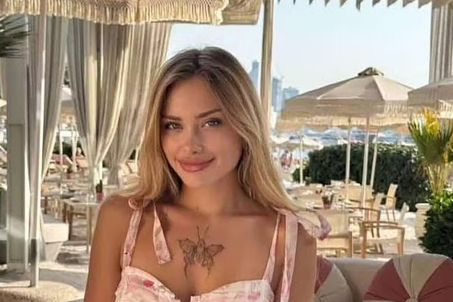 Mulher sorri com uma tatuagem de borboleta num cenário de praia