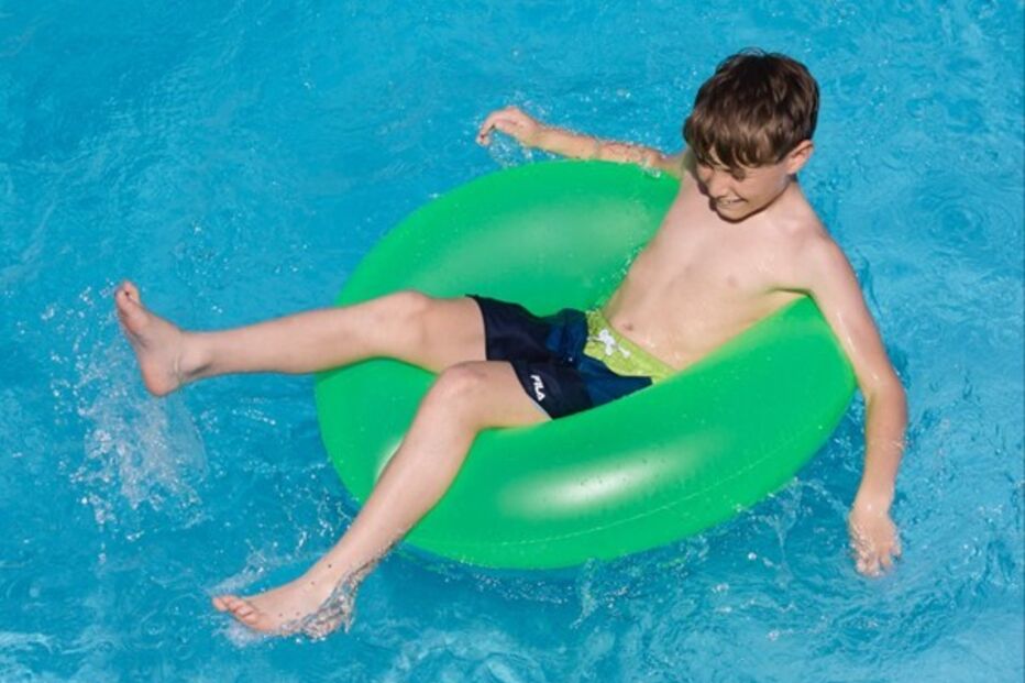Menino aproveita piscina com boia nas férias de verão