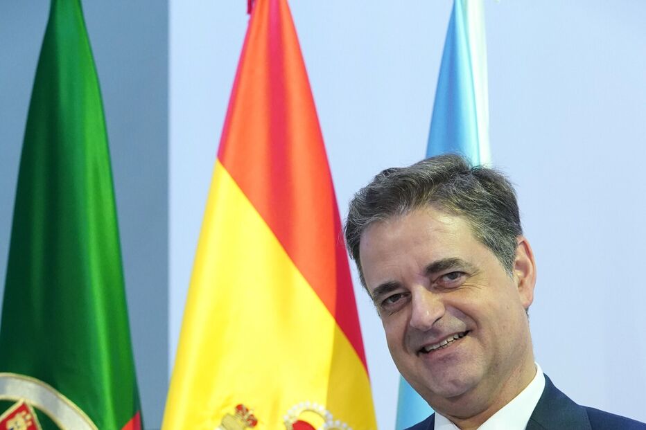 Um homem recebe condecoração com as bandeiras de Portugal e Espanha ao fundo