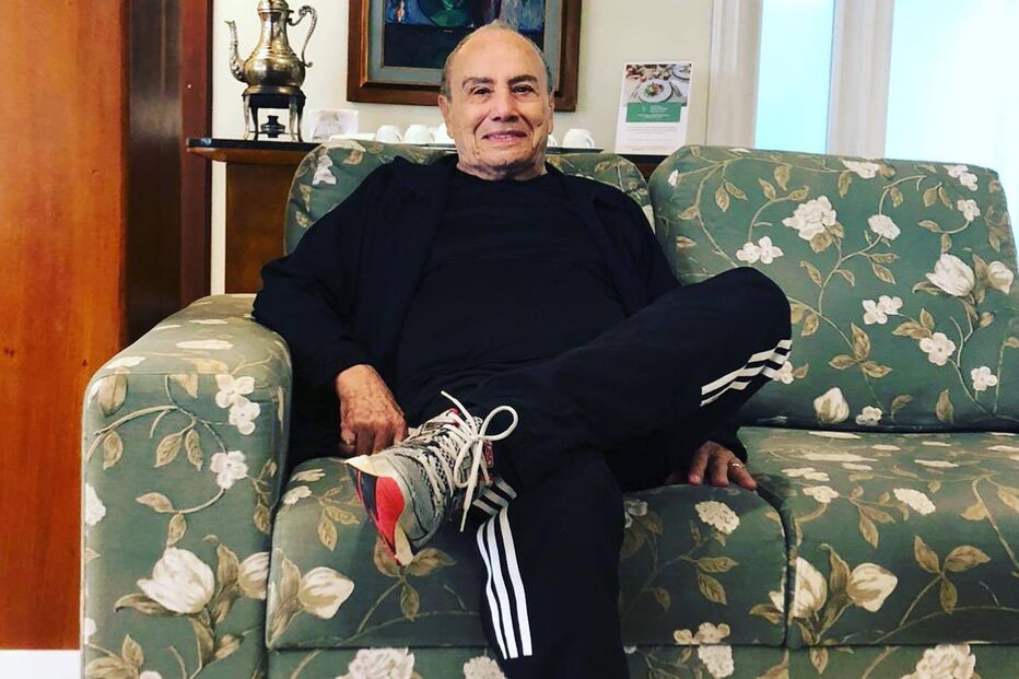 Homem sentado num sofá florido com roupa desportiva