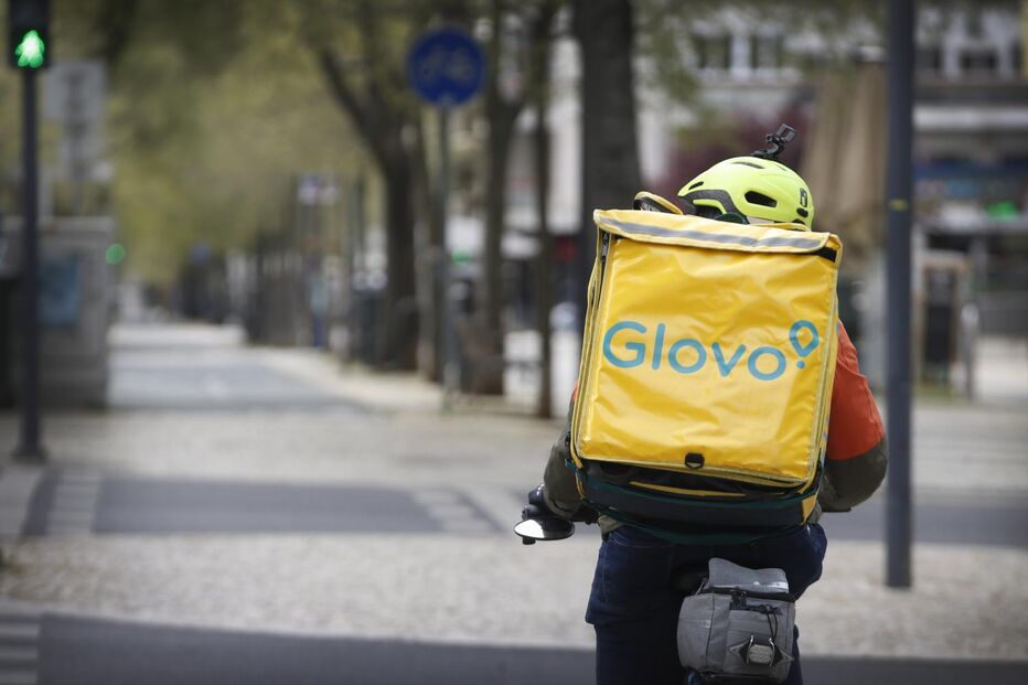 Estafeta da Glovo circula de bicicleta numa rua da cidade