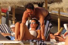 Casal relaxa na praia sob um chapéu de sol
