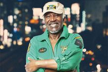 Homem sorri com fato verde e boné com símbolo da Jamaica