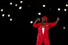 Artista atua no palco com microfone e fato vermelho