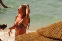 Pessoas aproveitam dia de sol na praia com mar calmo