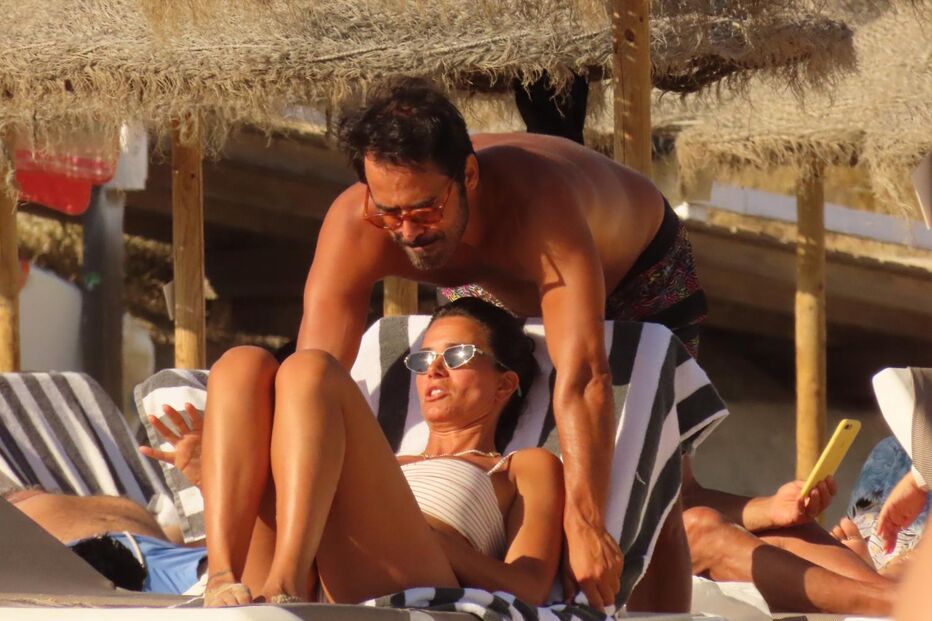 Casal relaxa na praia sob um chapéu de sol