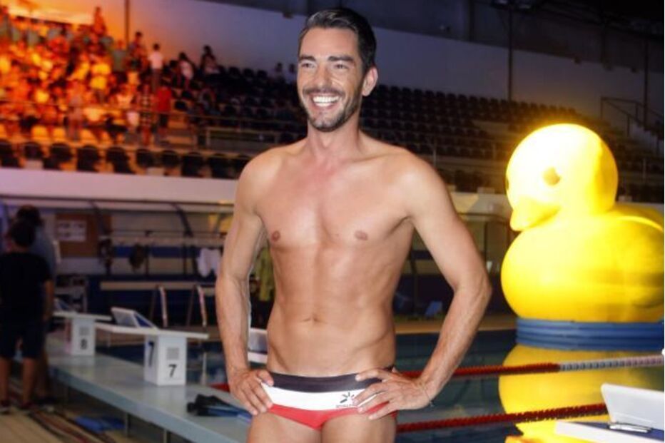 Atleta exibe físico numa piscina com pato gigante