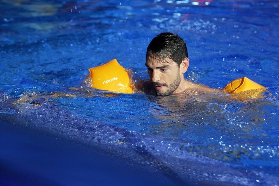 Homem nada com boias na piscina