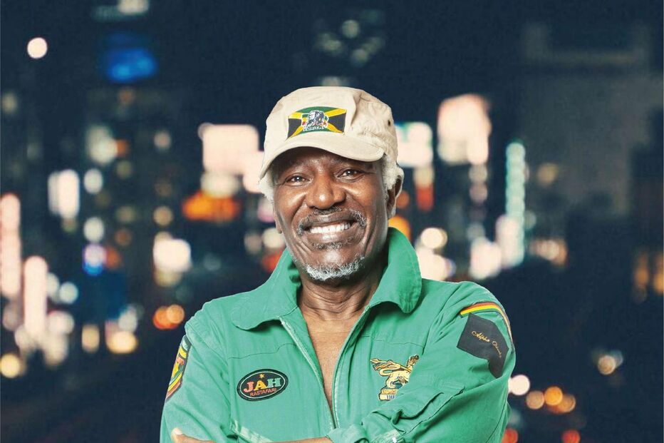 Homem sorri com fato verde e boné com símbolo da Jamaica