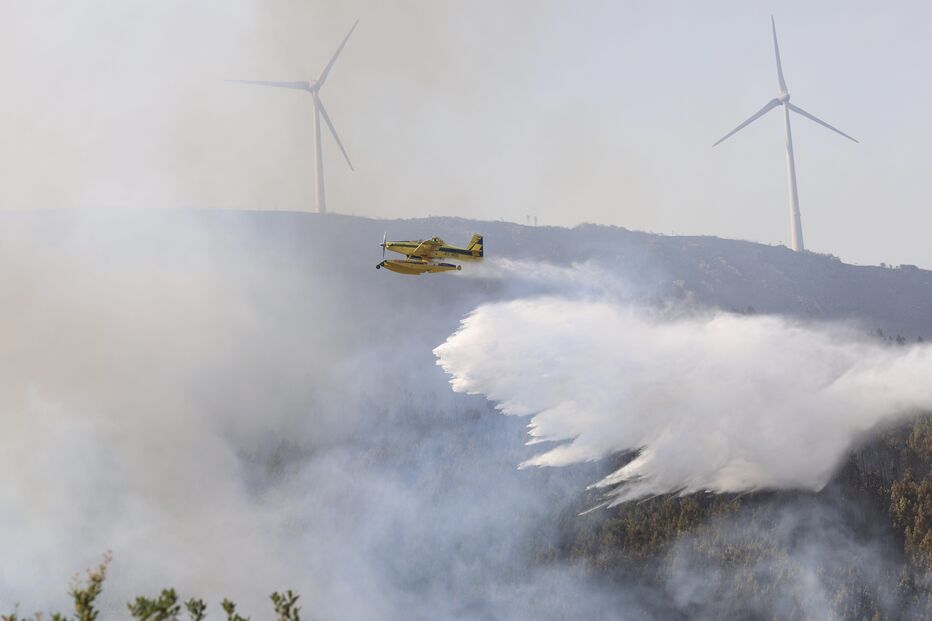 Aeronave combate incêndio com turbinas eólicas ao fundo