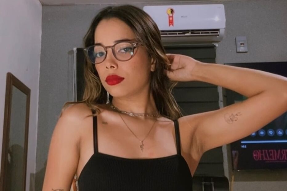 Mulher posa com blusa preta, calças brancas e óculos