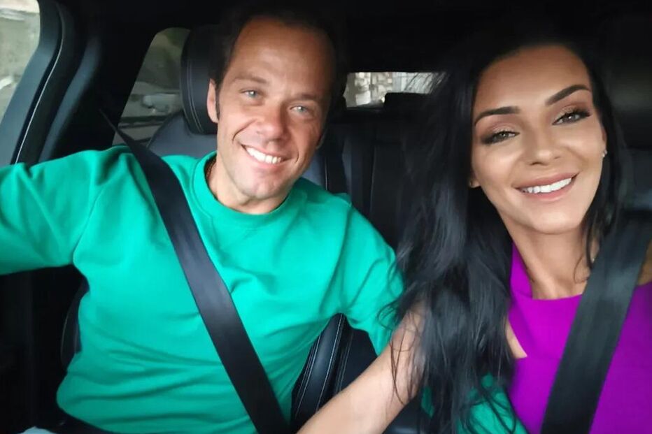 Casal sorridente posa dentro de carro com cintos de segurança