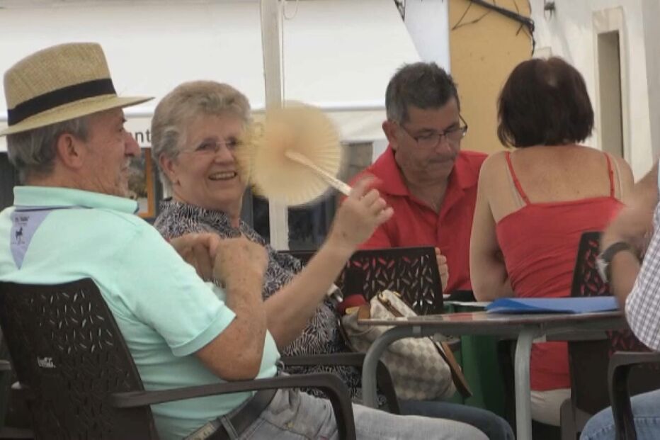 Onda de calor afeta saúde: idosos refrescam-se com ventoinha num café
