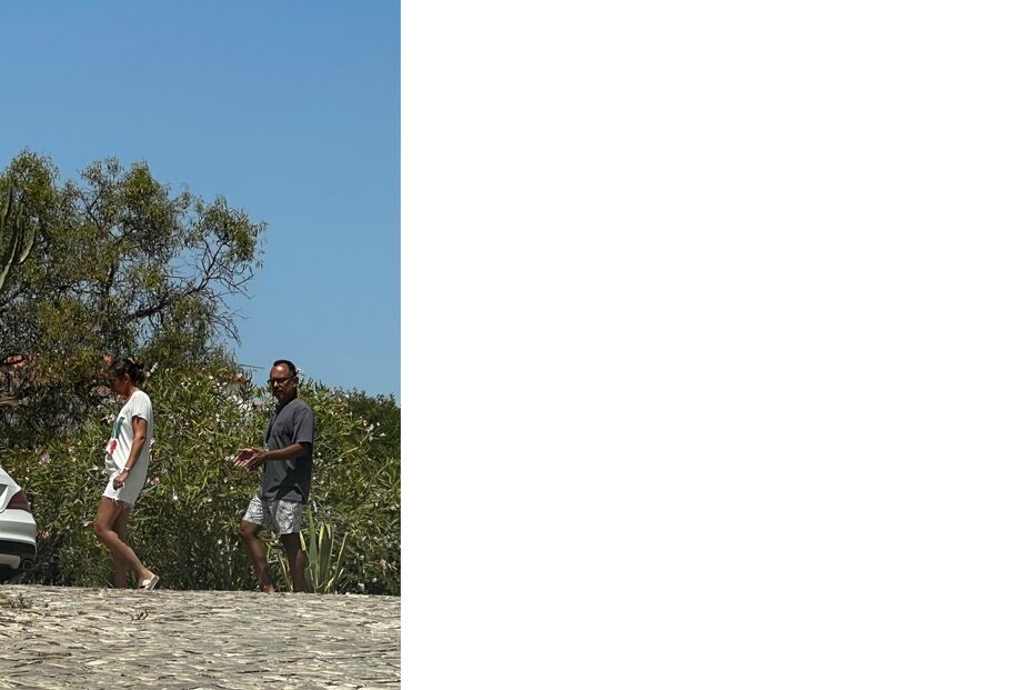 Casal caminha perto de vegetação e carro estacionado