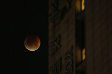 Lua de sangue vista num céu noturno ao lado de um edifício