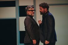 Dois homens em palco com fatos escuros