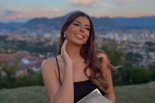 Mulher sorri com vista da cidade ao fundo