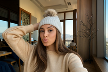 Mulher com gorro posa num espaço interior soalheiro