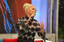 Mulher canta com um microfone num programa