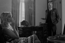 Mulher fuma num escritório enquanto um homem observa