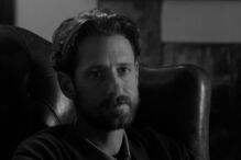 Retrato de um homem de barba num ambiente escuro