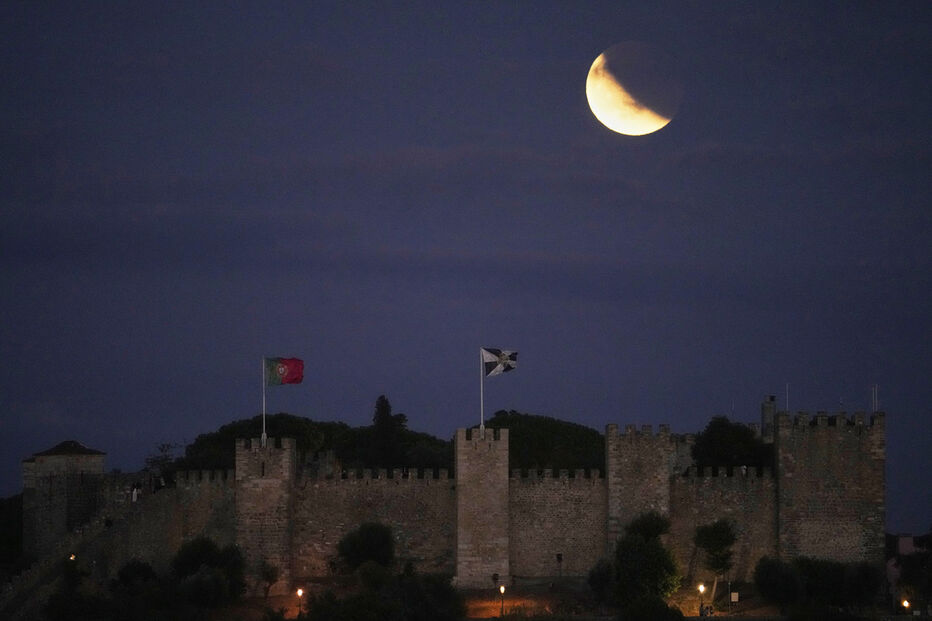 Castelo de Montemor-o-Velho sob eclipse lunar com bandeiras de Portugal e da localidade