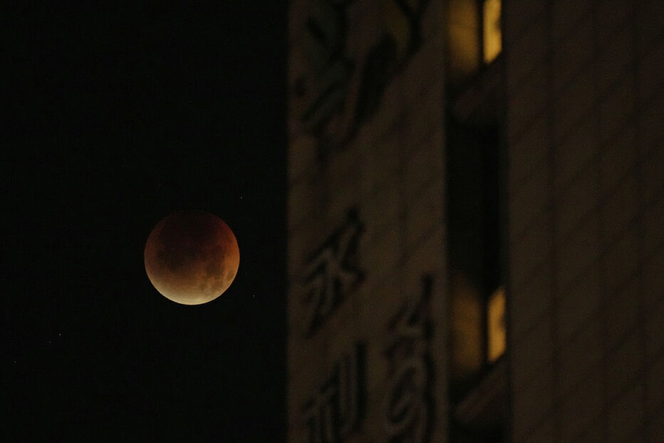 Lua de sangue vista num céu noturno ao lado de um edifício