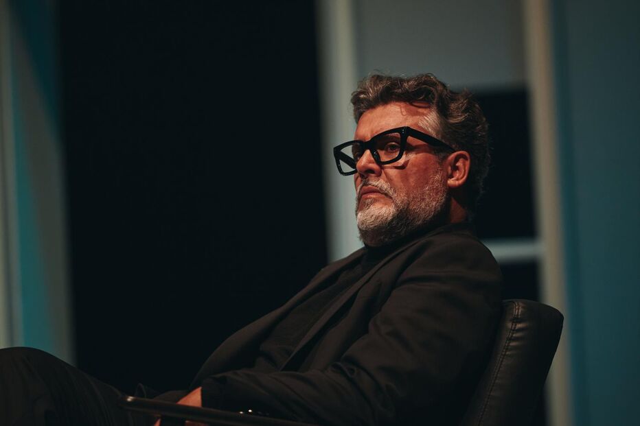 Um homem de óculos e fato preto num evento