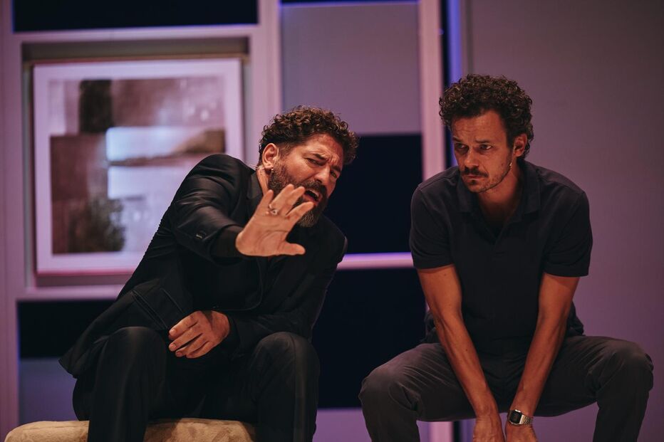 Dois homens sentados num palco durante uma apresentação