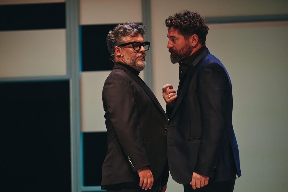 Dois homens em palco com fatos escuros