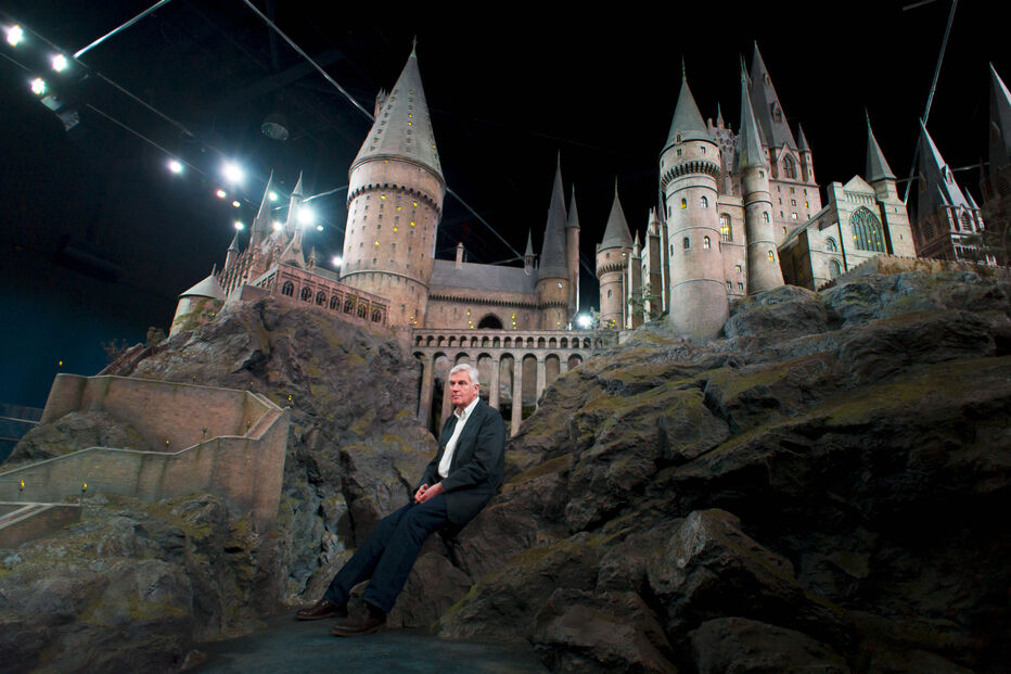 Stuart Craig junto a um modelo do Castelo de Hogwarts no Warner Bros Studio Tour em Londres