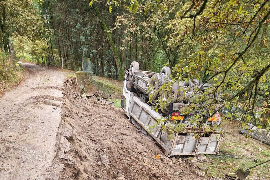Camião tombado numa zona florestal com destroços na berma da estrada