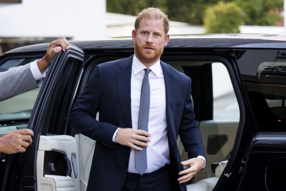 O Príncipe Harry sai de um carro com um fato azul e gravata
