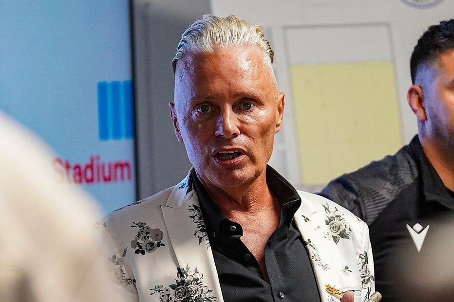 Homem faz discurso com blazer floral e cigarro na mão