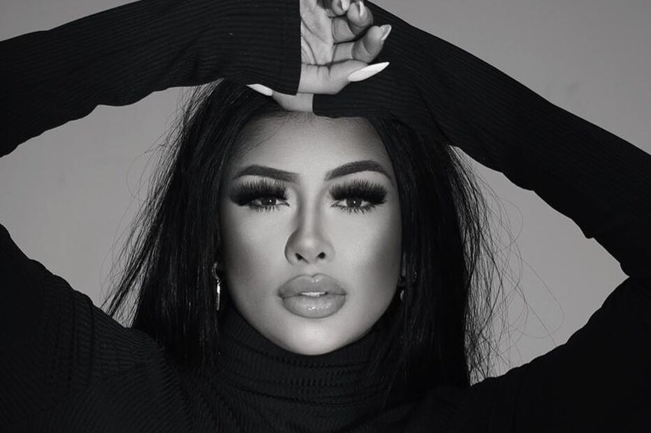 Mulher posa com blusa preta de gola alta e mãos na cabeça