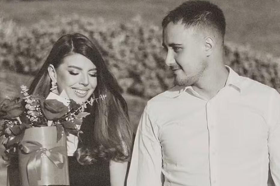 Um casal posa com um ramo de flores