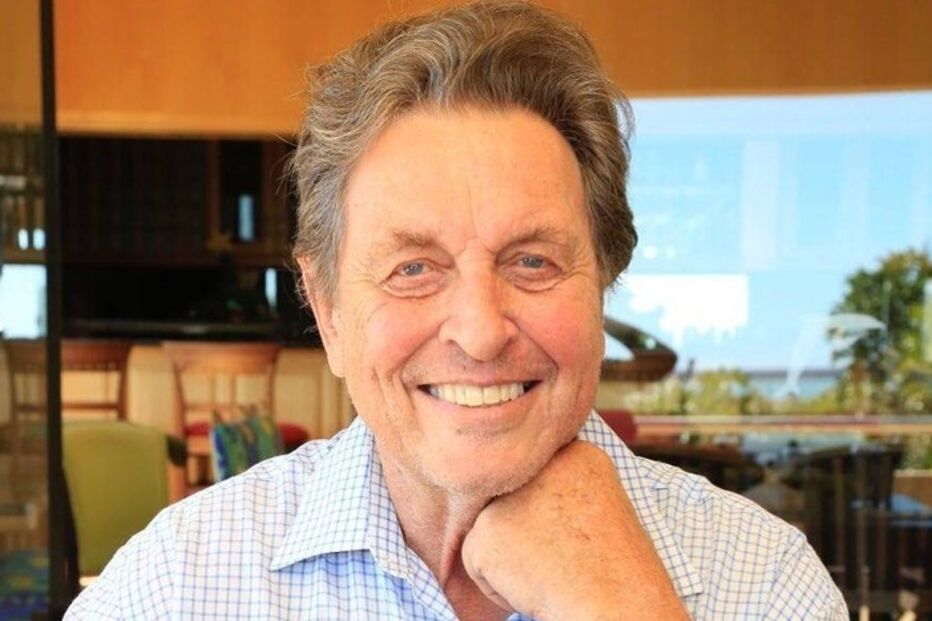 Homem sorri com camisa axadrezada e relógio no pulso