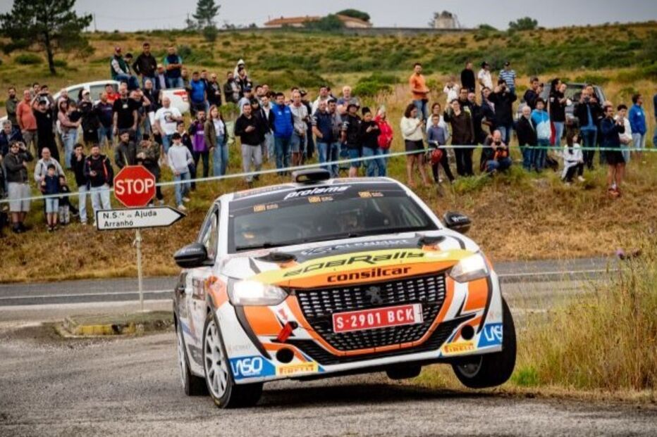 Carro de rali compete numa estrada com espetadores