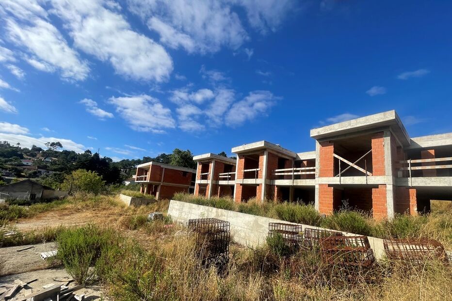 Construções inacabadas em área com vegetação sob céu azul