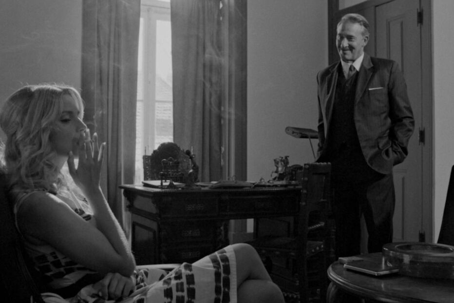 Mulher fuma num escritório enquanto um homem observa