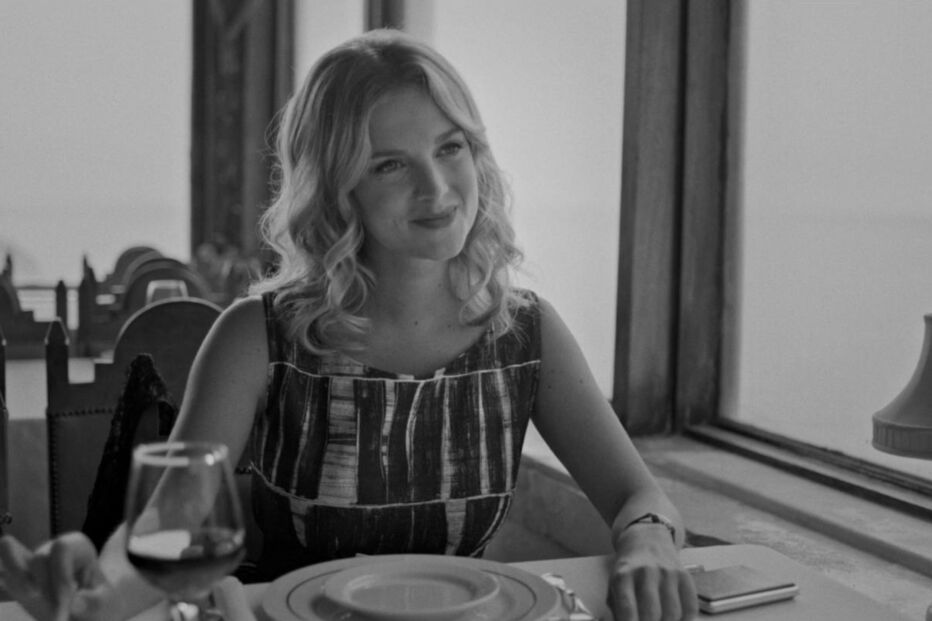 Mulher sorri à mesa perto da janela num restaurante