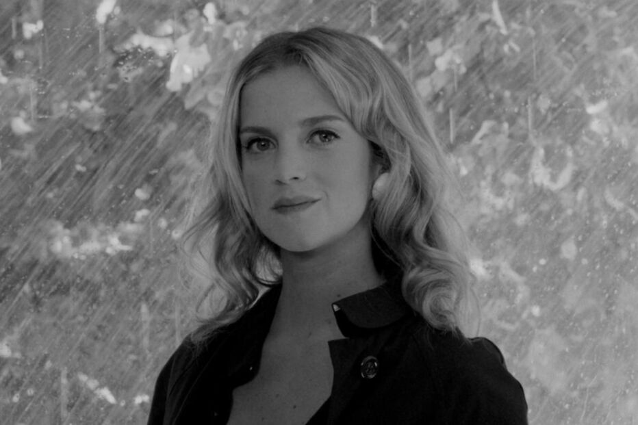 Retrato em preto e branco de uma mulher com cabelo ondulado e casaco escuro