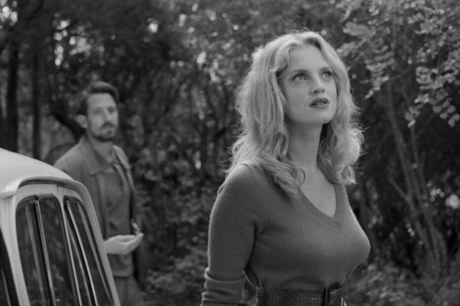 Fotografia a preto e branco com mulher e homem perto de carro