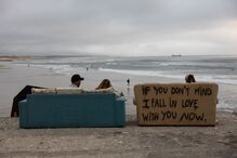 Praia com vista para o mar e sofás com mensagem de amor