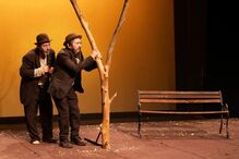 Interpretação da peça com dois homens e um banco em palco