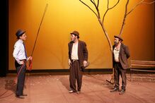 Peça com três atores em palco e uma árvore seca