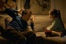 Pai gesticula enquanto conversa com filha no sofá