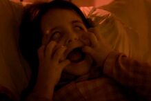 Criança assustada na cama com olhos brancos e boca aberta