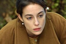 Retrato de mulher com flor no cabelo e olhar pensativo