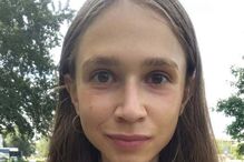 Mulher sorri para a câmara com corrente dourada e t-shirt branca